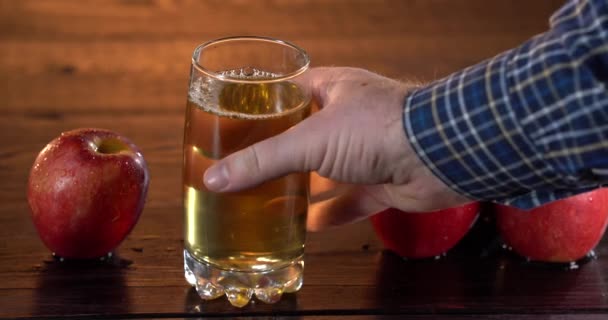 Mans main prend le verre avec du jus de pomme frais de la table — Video