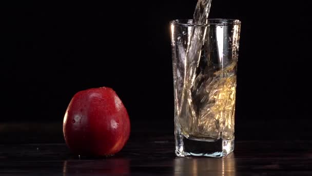 Appelsap gieten in glas op witte tafel. Citrussap spat in slow motion — Stockvideo