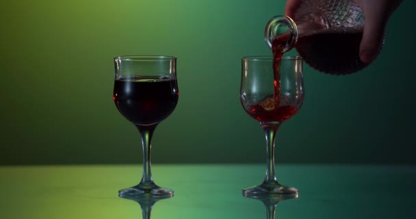 Yeşil-sarı arka planda bardağa kırmızı şarap dökülüyor. — Stok video