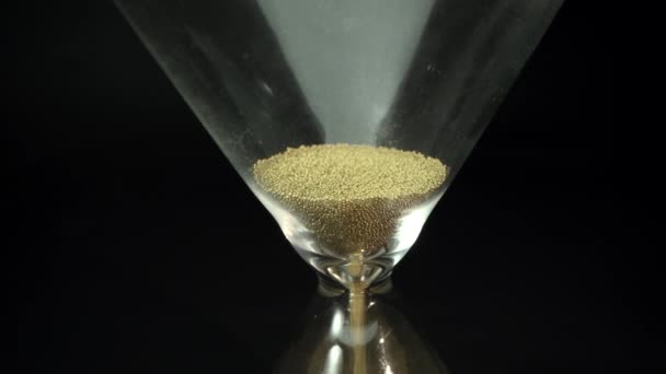 Timglaset Countdown Sand faller i en glasflaska på svart bakgrund. Med tiden. Tid är pengar. Makro — Stockvideo