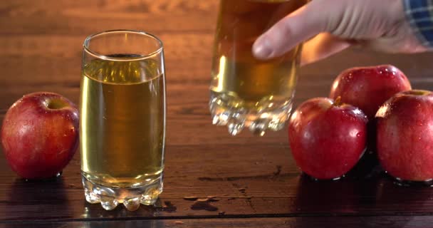 L'homme pulvérise du jus de pomme frais et sain sur une table en bois. Deux verres avec du jus à la surface. Jus savoureux dans la journée d'été. Des pommes sur la table aussi — Video