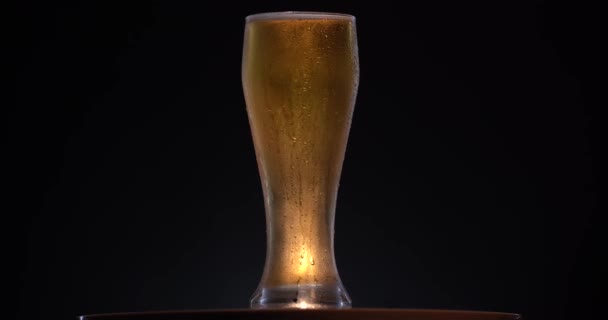Primo piano della birra scura. Pinta di birra artigianale fredda isolata su fondo nero opaco, rotazione 360 gradi. Bicchiere di birra con gocce d'acqua. 4K video UHD 3840x2160 — Video Stock