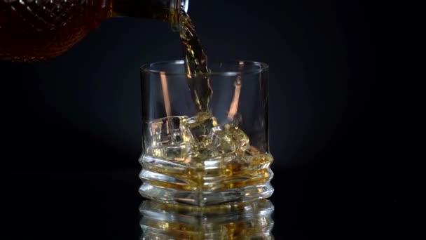 Whiskey Bourbon dituangkan ke dalam gelas es gerak lambat jatuh dekat tembakan makro. Alkohol di bar. Kaca dengan banyak es batu. Jumat malam — Stok Video