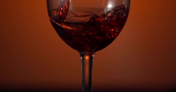 Verter el vino de una botella en un vaso sobre el fondo de una pared marrón. Primer plano del vino tinto en una copa. Concepto de alcohol. Ideal para publicidad — Vídeos de Stock