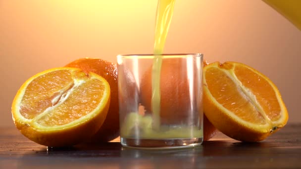 ガラス瓶からオレンジジュースをグラスに入れる。新鮮なオレンジジュースのガラスを閉じます。天然成分から健康的な朝食を準備します。自家製フルーツジューステーブルの上。オーガニックビタミンドリンク — ストック動画