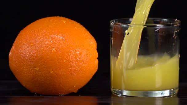 Tiro de movimento super lento de suco de laranja fresco sendo derramado em um copo — Vídeo de Stock