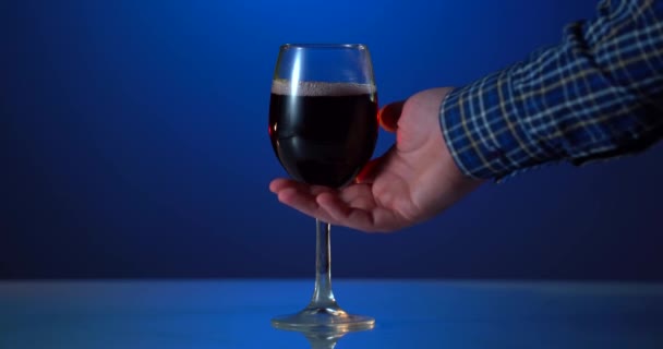Mans Hand nimmt das Glas mit Rotwein vom Tisch. Sommelier verkostet Wein im Keller und schenkt einen hervorragenden Rotwein in ein Glas ein — Stockvideo