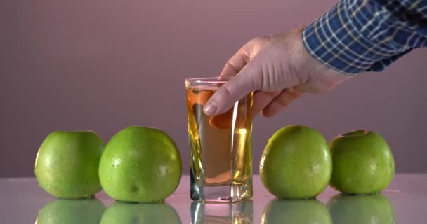 Mans 'ın eli bardağı elma suyuyla alıyor. Taze yeşil elmalar masada. — Stok video