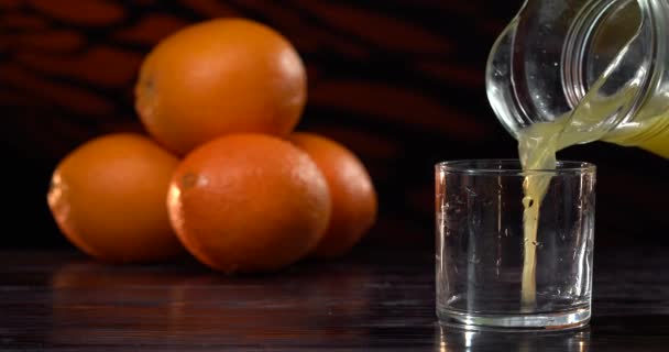 Orangensaft ins Glas gießen. Schöner Hintergrund. Frische Orangen liegen auf dem Tisch — Stockvideo