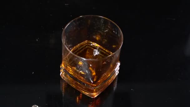 Led se ve velmi pomalém záběru ponořil do sklenice whisky. Horní pohled. Koncept alkoholu. Uvolněte se po náročném a dlouhém týdnu v práci. Před víkendu — Stock video