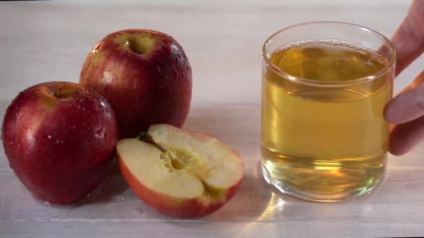 Erkek eli bardağı elma suyuyla beyaz masaya koyar.. — Stok video