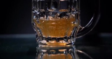 Bira bardağa döküldü. Siyah arka plan. Cam sehpayı yansıt. Barmen bardağa taze bira dolduruyor. Hafta sonu konsepti.