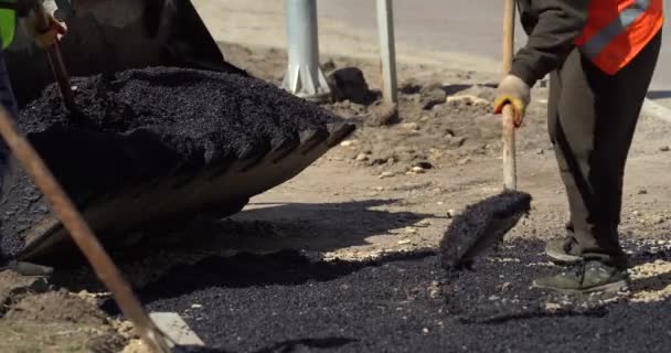 Jalan Konstruksi dan Perbaikan Karya. Pekerja Leveling Fresh Asphalt di Situs Konstruksi Jalan. Pekerja menggunakan Asphalt Lute. Kerjasama Pada Konstruksi Jalan. — Stok Video