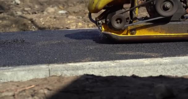 Compactor is driving over freshly loured asphalt and compresses it on the road to fix a hole. Дорожная проблема. — стоковое видео