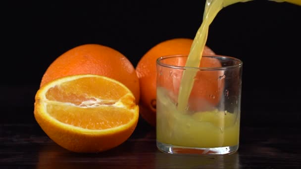 Super Slow Motion Shot de verter jugo de naranja fresca en el vaso. Fondo negro — Vídeo de stock