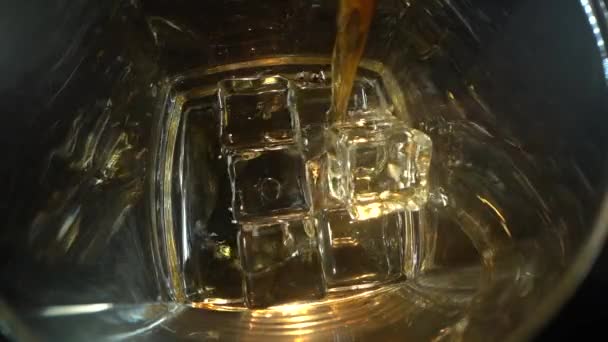 ウイスキーは氷をグラスに注いだ。暗い背景で。最上階だ。マクロ・ショット。ガラスの中の氷。アルコールの概念. — ストック動画