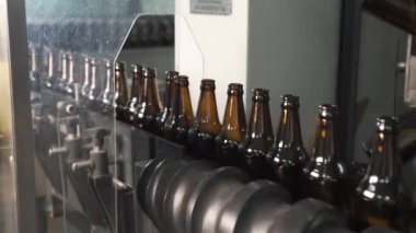 Bira fabrikasında bira şişeleme teknolojisi. Fabrikada tek sıra halinde boş kahverengi şişeler. Şişeler Glass Bottle Factory 'de konveyör bandında ilerliyor. Temiz bira şişeleri konveyör boyunca ilerliyor..