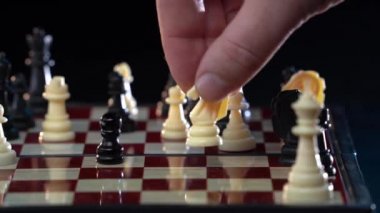 Satranç oynayan adama yaklaş ve siyah arka planda beyaz kaleyle hamle yap. İş adamı satrançta stratejik hamle yapıyor. Entellektüel hobi, strateji kavramı