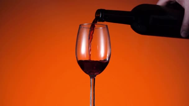 El vino tinto forma una ola hermosa. Vino que vierte en copa de vino en el fondo dramático. Primer plano de tiro. Movimiento lento de verter vino tinto de la botella en la copa. — Vídeo de stock