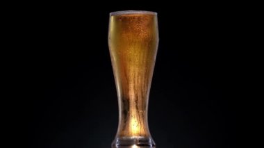 Bira şişesinin üzerine su damlası dokusu. 4k 'lık atışta biralı döner bardak.