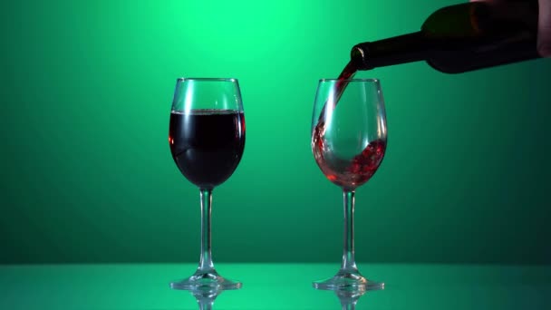 Pouring red wine into the glass against green background — Stock Video