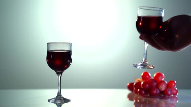 Red wine forms beautiful wave. Wine pouring in wine glass over white background. Close-up shot. Slow motion of pouring red wine from bottle into goblet. Low key — Stock video