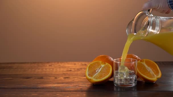 Jugo de naranja saludable en un vaso y naranjas. Jugo de salpicadura de imágenes en cámara lenta. Comida y bebida saludables. Humor de verano. Concepto vegano — Vídeos de Stock