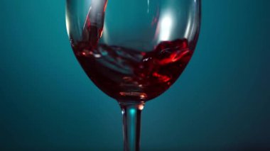 Kırmızı şarap mavi arka planda cam bir fünyede güzel bir dalga oluşturur. 4k