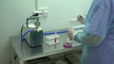 Laboratuvarda kimyasal bileşiklerle dolu cam test tüplerinin görüntüsü. Test tüpünde mavi renkli kimyasal madde var. Şarjör hazır..