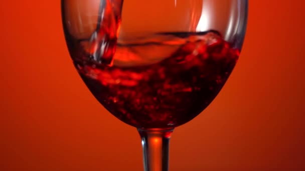 Vierte vino tinto en una copa sobre el fondo rojo. Imágenes de 4k — Vídeo de stock