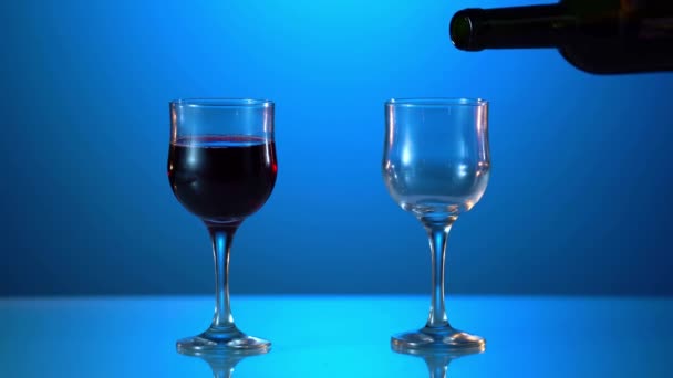 Mává červeným vínem ve sklenici na rozostřeném modrém pozadí. Krásné záběry pro reklamu na víno. Zavřít video procesu míchání vína uvnitř poháru. Snímek na fotoaparátu ARRI ALEXA v pomalém pohybu . — Stock video