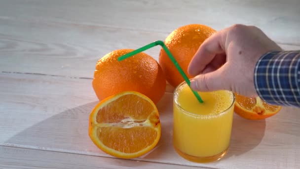 ガラスとオレンジの健康的なオレンジジュース。ジューススローモーション映像。夏の気分。暑い日の健康的な飲み物 — ストック動画