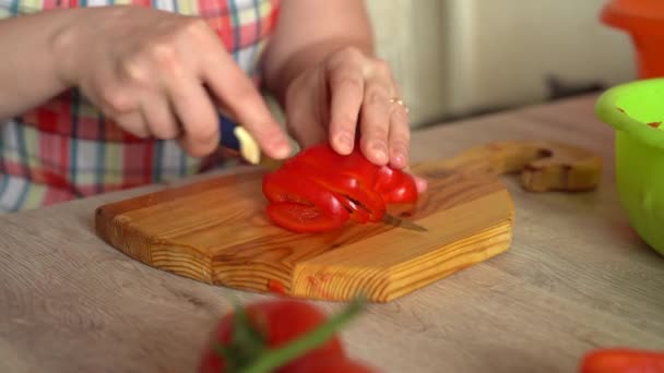 Dívka krájí čerstvou nakrájenou červenou papričku. Horní pohled. Dřevěné řezací prkno. žena, co vaří v kuchyni. Bílá dívka — Stock video