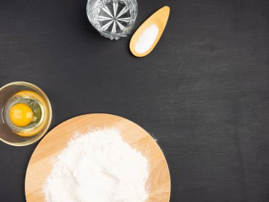 Tahtada un, yumurta, su, siyah ahşap arka planda tuz. Mutfak konsepti