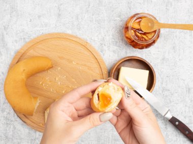 Kadın bir somuna yağ ve reçel sürdü. Mutfak konsepti