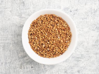 Beyaz beton arka planda seramik beyaz bir fincanda karabuğday. Diyet ve kilo verme konsepti. Üst görünüm