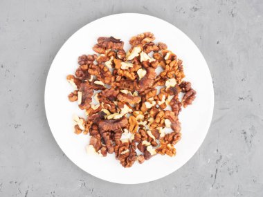 Gri beton arka planda beyaz tabakta kabuklu ceviz. Sağlıklı beslenme konsepti. Üst görünüm 