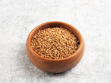 Beyaz beton arka planda tahta bir fincanda karabuğday. Diyet ve kilo kaybı kavramı