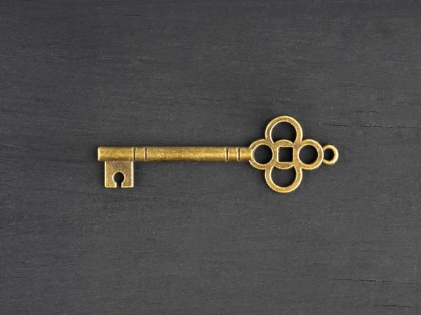 Bronze antique key on black wooden background with copy space