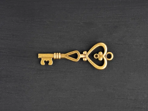 Bronze antique key on black wooden background with copy space