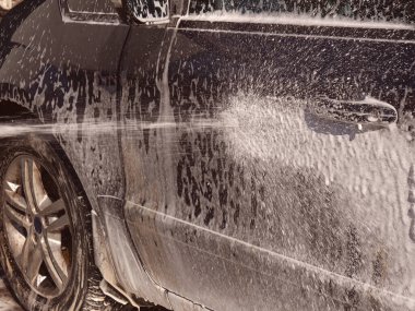 Arabayı su ve şampuanla yıka, su jeti arabanın yan tarafına doğru gidiyor.