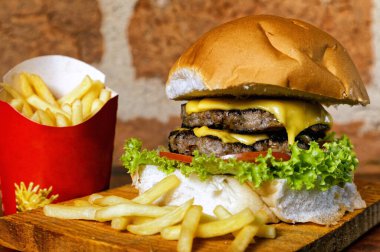 Domuz pastırması, yeşil salata, marul, ahşap tahtanın altında domates ve yanında patates kızartması.