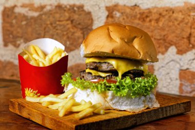 Domuz pastırması, yeşil salata, marul, ahşap tahtanın altında domates ve yanında patates kızartması.