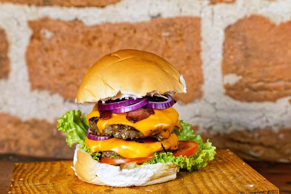 Yumurtalı lezzetli burger sandviç, domates peyniri, pastırma ve marul ahşap tahtanın altında kırsal duvarda arka planda.