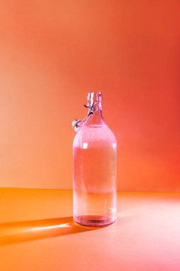 Güneş tarafından aydınlatılan temiz içme suyu dolu cam şişe..