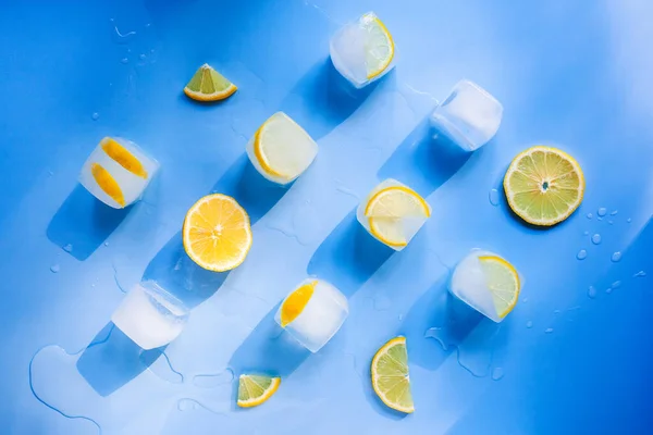 Composição geométrica moderna das fatias congeladas de limão e cubos de gelo em um fundo azul — Fotografia de Stock