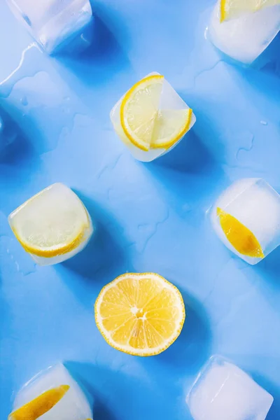 Moderní geometrické složení zmrazených plátků citronu a kostek ledu na modrém pozadí — Stock fotografie
