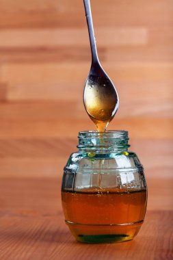 bir kaşık Sarı zemin üzerine cam kavanoza damlama tatlım