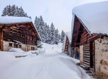 Issız bir dağ evi ve İsviçre Alpleri 'nin yukarısında Davos yakınlarında taze toz karla kaplı köyler.