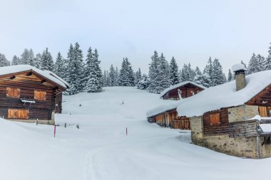 Issız bir dağ evi ve İsviçre Alpleri 'nin yukarısında Davos yakınlarında taze toz karla kaplı köyler.
